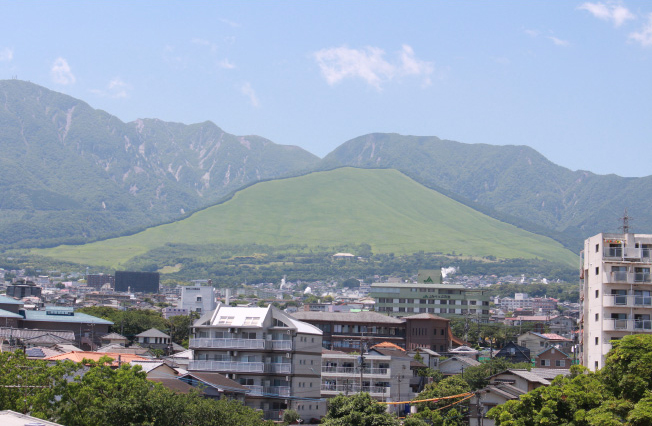 石垣キャンパスから鶴見岳を眺望する。学歌にも描かれる扇山のスロープは、緑色、ラクダ色、白色へと季節で色を変える。